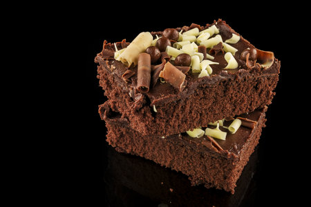 Piece of chocolate cake with nuts on a black reflective background.の写真素材
