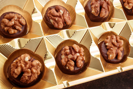 Delicious chocolate candies with walnuts in golden box close up