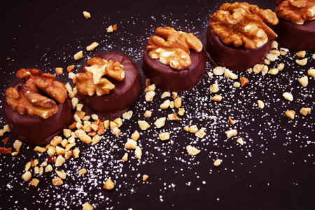 Chocolate candies with nuts on black background. Toned.の写真素材