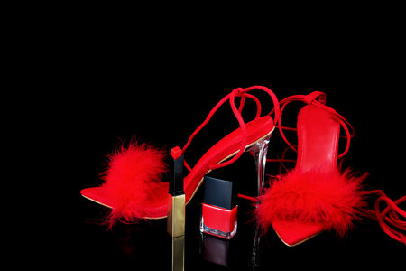 Red high heel shoes with red fur and nail polish on black backgroundの写真素材