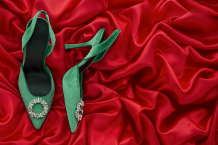 Green high heel shoes on red satin background with copy space.の写真素材