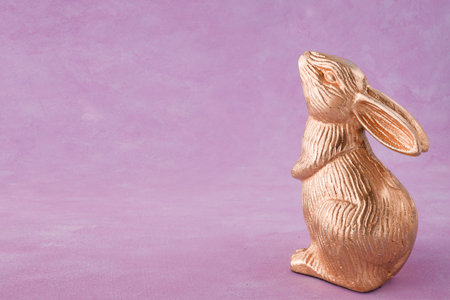 Easter bunny figurine on a purple background with copy space.