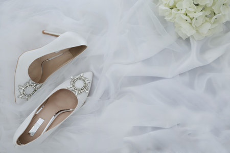 Wedding shoes on a white background with a bouquet of flowersの写真素材