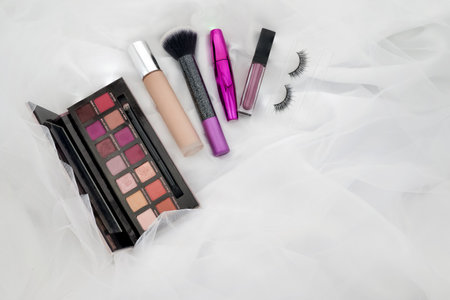 collection of make up and cosmetic beauty products arranged on white fabric backgroundの写真素材