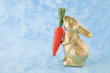 Easter bunny with carrot on a blue background. Copy space.