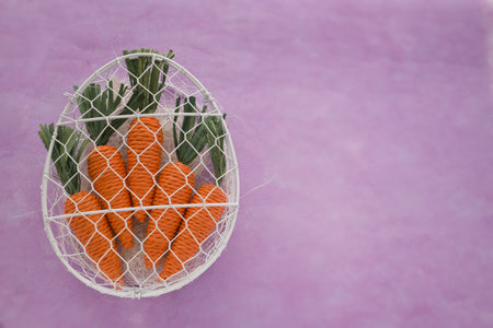 Carrot in a wire basket on a pink background with copy spaceの写真素材
