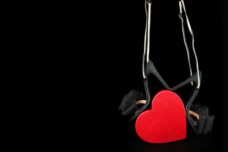 Black high-heeled shoes with a red heart on a black backgroundの写真素材