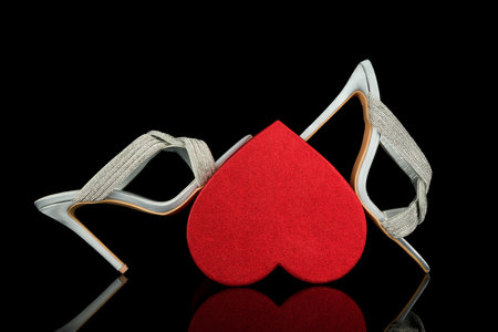 Red heart and a pair of white leather chairs on a black backgroundの写真素材