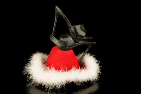 Black high heel shoes in Santa Claus hat isolated on black background.の写真素材