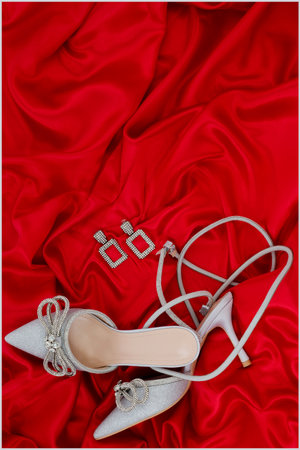 Wedding rings and shoes on red satin background, top viewの写真素材