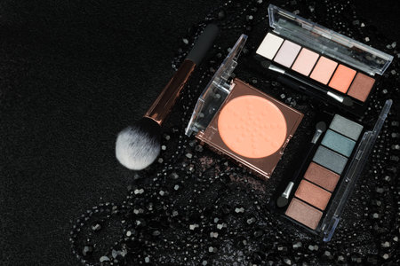 Makeup brushes, eye shadows, powder and cosmetics on black backgroundの写真素材