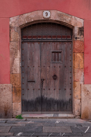 Old wooden door on a red wall in the old town of Catania, Sicily, Italyの写真素材