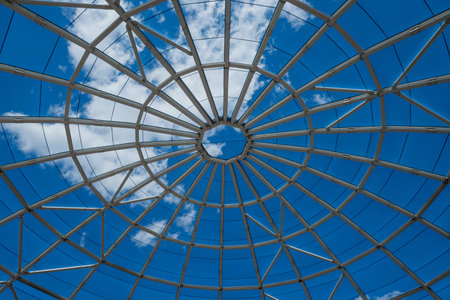 Glass dome with blue sky and white clouds. Abstract architecture background.