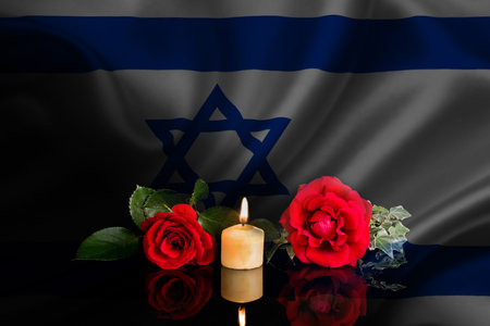 Israel flag, burning candle and red roses on a dark background.の写真素材