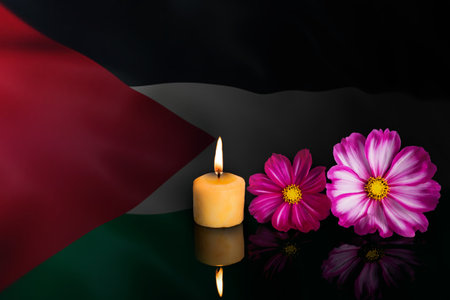 palestine flag with a lit candle and flowers on a black backgroundの写真素材