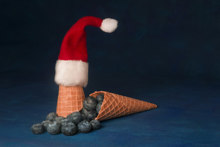 Ice cream cone with Santa Claus hat, blueberries and dark blue backgroundの写真素材