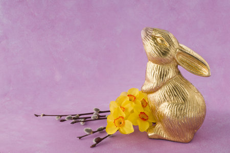 Easter bunny with yellow narcissus flowers and willow branches on pink backgroundの写真素材