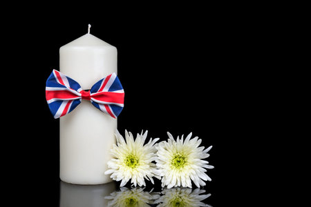White candle with red and blue bow isolated on black background with chrysanthemum