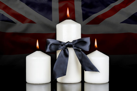 Four burning candles with black ribbon on the Union Jack flag background.の写真素材