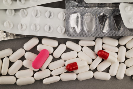 Close up of pills and capsules in blister pack on grey background.