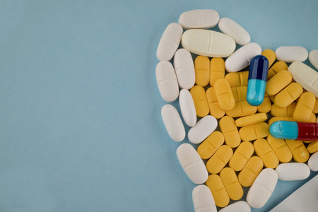 Pills and capsules on blue background with copy space for text.