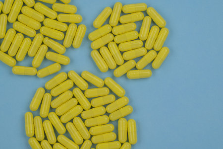 Yellow pills on blue background. Top view. Copy space for text.