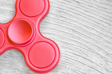Red fidget spinner on background white wood. Stress relieving toy.