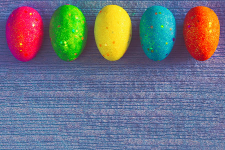 Decorated colorful Easter eggs on blue knitted background with space for text. Trendy minimal pop art style and colors.の写真素材