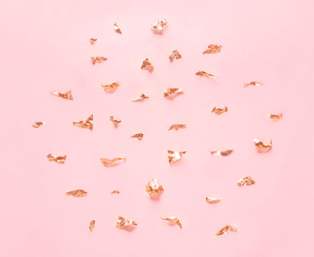 Golden elements and crumbs foil on pastel pink paper background.の写真素材