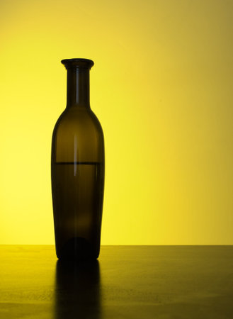 Genuine Italian old oilive oil bottle, part silhouetted by yellow light   の写真素材