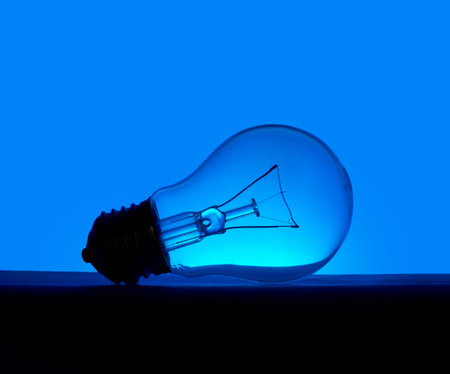 Pretty old incandescent light bulb, lying over blue