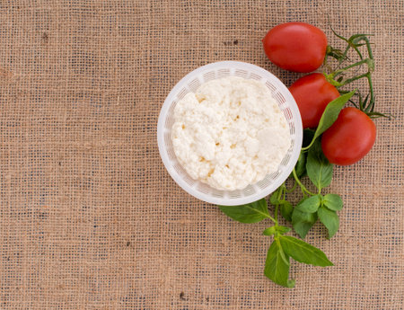Fresh ricotta cheese in mould with tomatoes, basil. Mediterranean diet essentials.