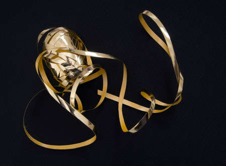 Pretty gold gift ribbon on black fabric.の写真素材