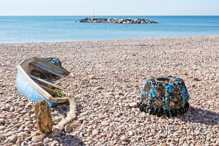 Fishermen no more. Abandoned smallboat and lobster pot on beachの写真素材