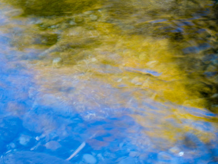 Autumn leaves and blue sky reflections in stream
