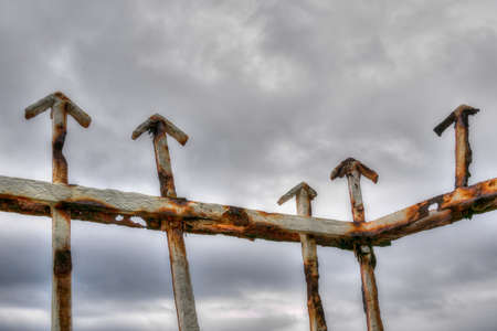 Old railing arrows point up. Grey clouds background.の写真素材