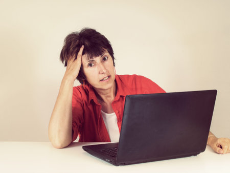 Middle aged woman working on laptop. Retro filtered image.