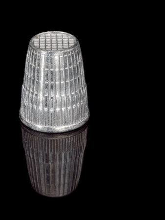 Silver colour plastic thimble, reflected.