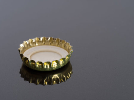 Beer bottle cap with reflection. Grey background.