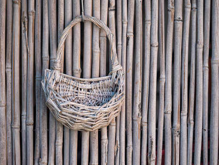 Rustic objects. Wicker basket and bamboo fence background.の写真素材