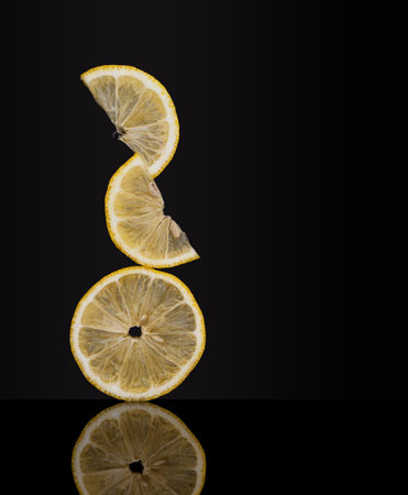 Creatively balanced fresh lemon fruit slices on dark background. Unusual photo. Seem to defy gravityの写真素材
