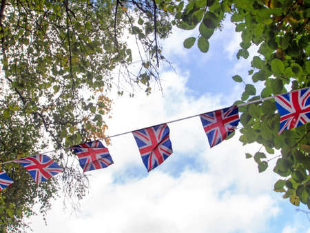 Red, white and blue festive bunting flags against sky background. Union Jack, UK flags blowing in the wind. Brexit maybe.の写真素材