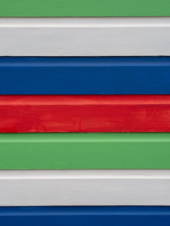 Brightly painted horizontal stripes of wood, from old beach hut. Background.