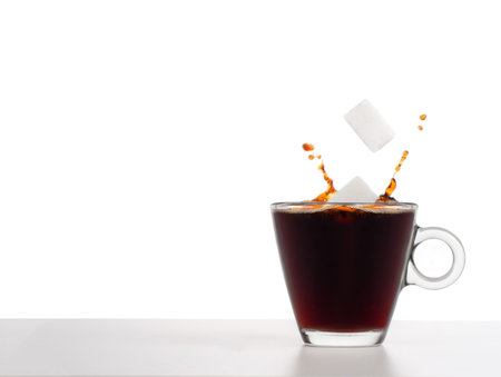 Sugar cubes falling into coffee with splash, health concept. Plain background for copyspace. Glass...
