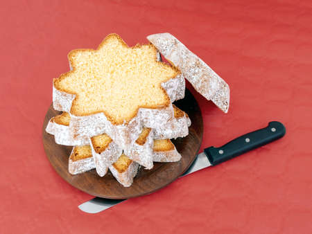 Sliced pandoro, Italian sweet yeast bread, traditional Christmas treat. With knife on red. Overhead flat lay view.の写真素材
