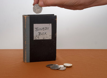 Vintage swear box, with UK coins, money and hand.