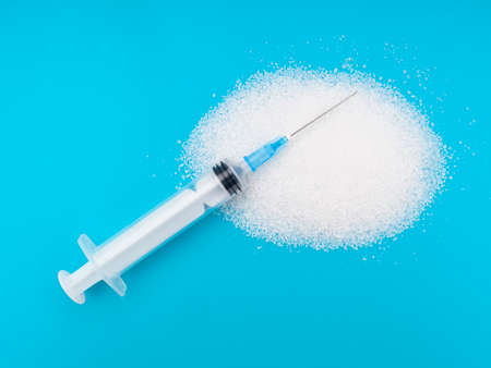 White granulated sugar on bright colourful background with syringe. Unhealthy eating, diabetes health risks etc.の写真素材
