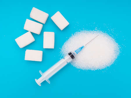 White sugar, cubes and granulated, on bright colourful background with syringe. Unhealthy eating, diabetes health risks etc.の写真素材