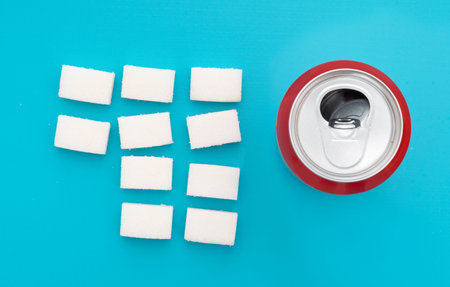 Unhealthy food concept - sugar in carbonated drinks. Sugar cubes and fizzy cola drink can. Flat lay,...