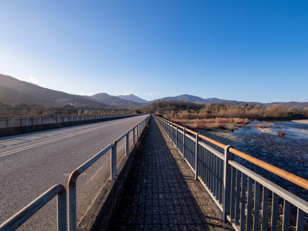 Vanishing point on bridge over Magra river in Lunigiana, near Aulla. Winter landscape. North...